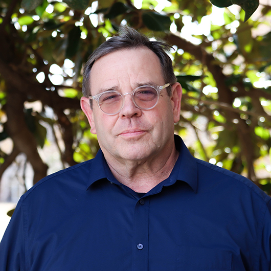 man with clear framed glasses, wearing a dark blue dress shirt