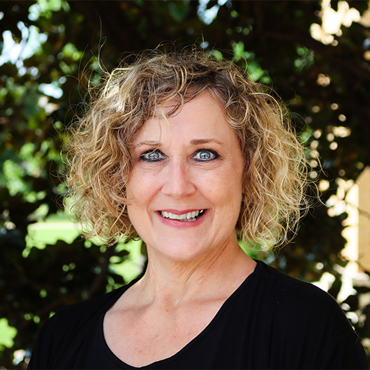 Woman with wavy blonde hair wearing a black shirt