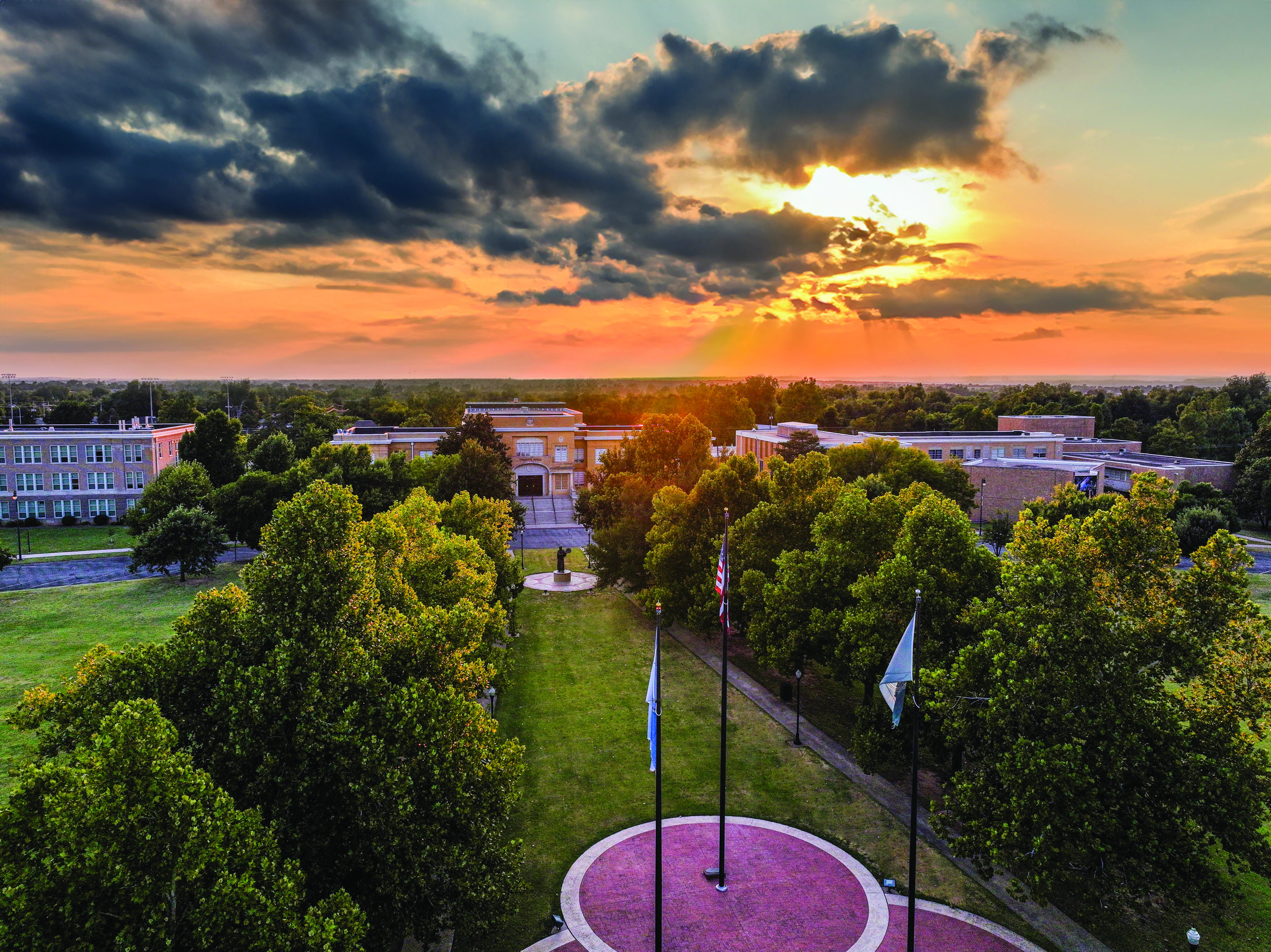 Aerial view of the USAO campus and its tree-lined walkways beneath a colorful sunset.