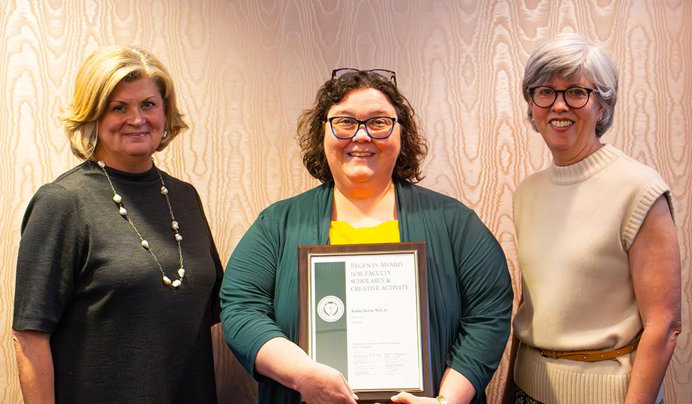 woman in green and gold with award